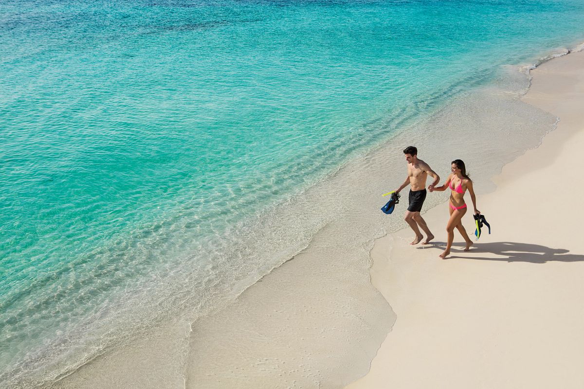 Couple enjoying a beach walk with snorkel gear at Secrets Akumal Riviera Maya