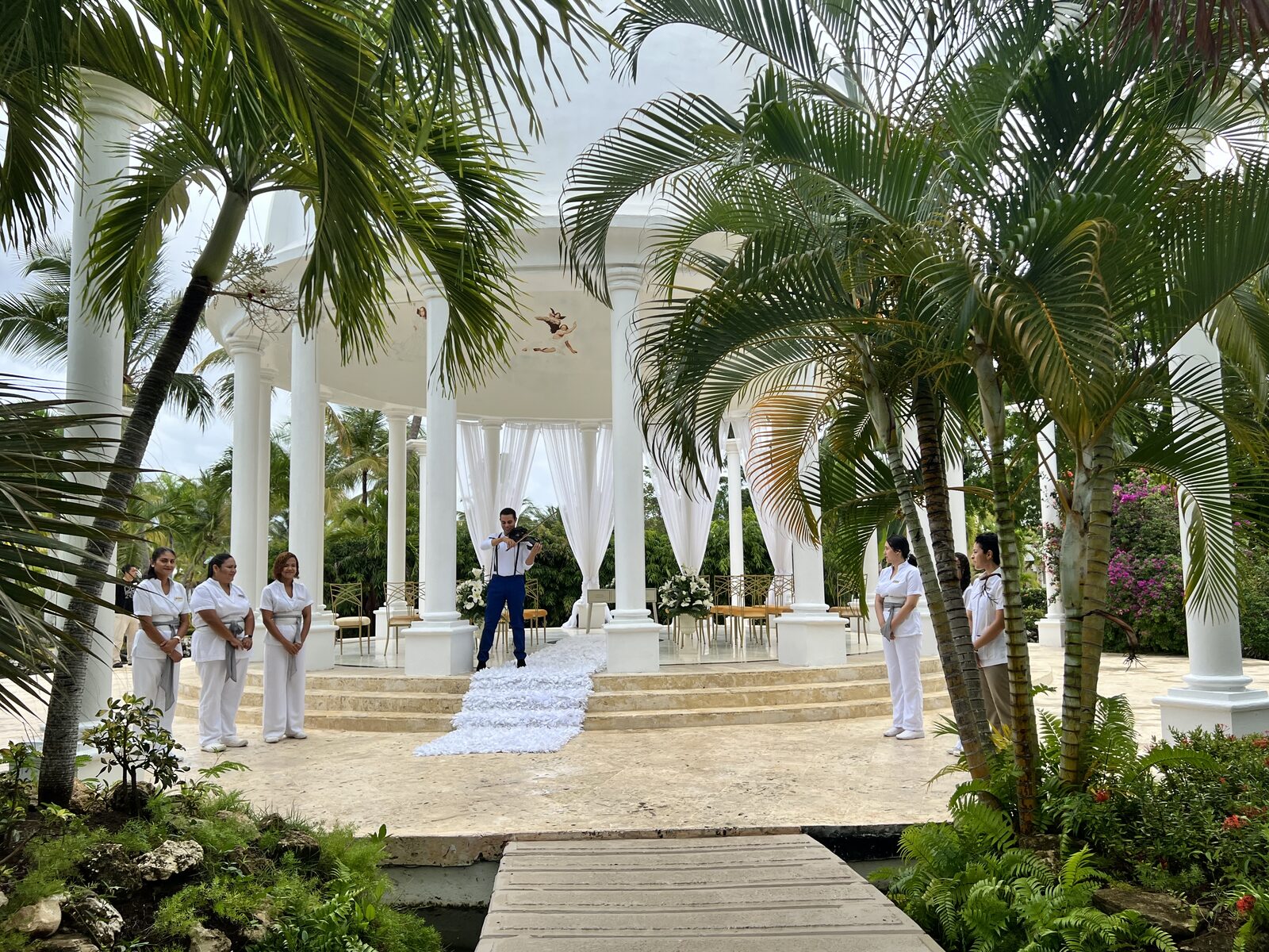 A violinist playing during a beach wedding gazebo ceremony in Mexico, the kind of resort-coordinated live music that the wedding department books through their long-standing vendor list