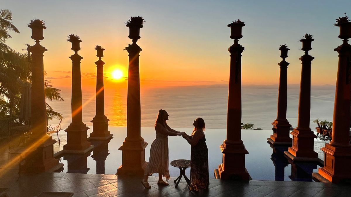 Couple holding hands at a sunset infinity pool overlooking the ocean in Costa Rica