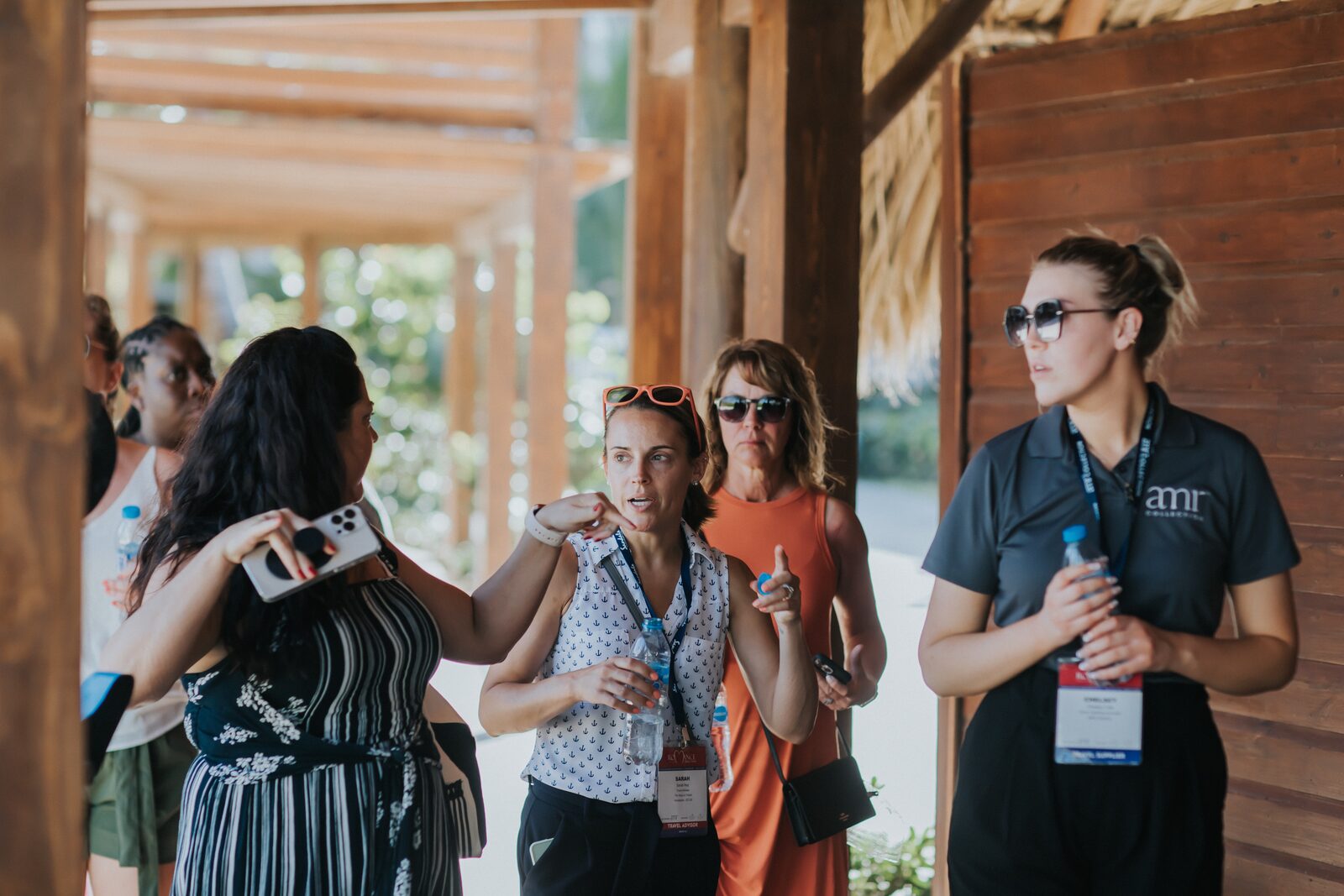 A destination wedding advisor talking with a group of travelers under a resort palapa — the kind of pre-arrival conversation where transfer tier gets matched to actual budget, group size, and arrival timing instead of guessed at online