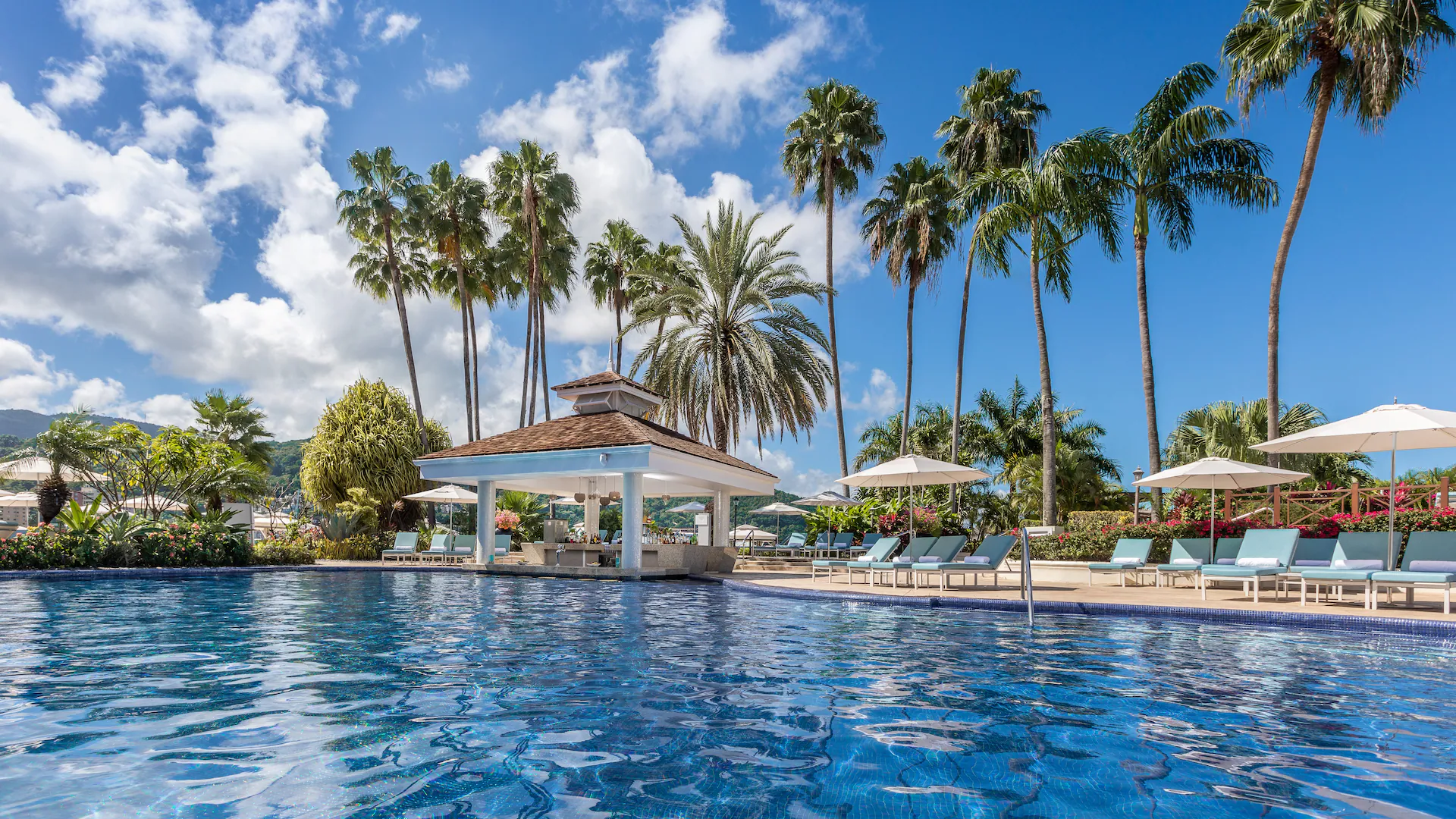 Jamaican resort pool ringed by tall palm trees with a dramatic Caribbean sky overhead