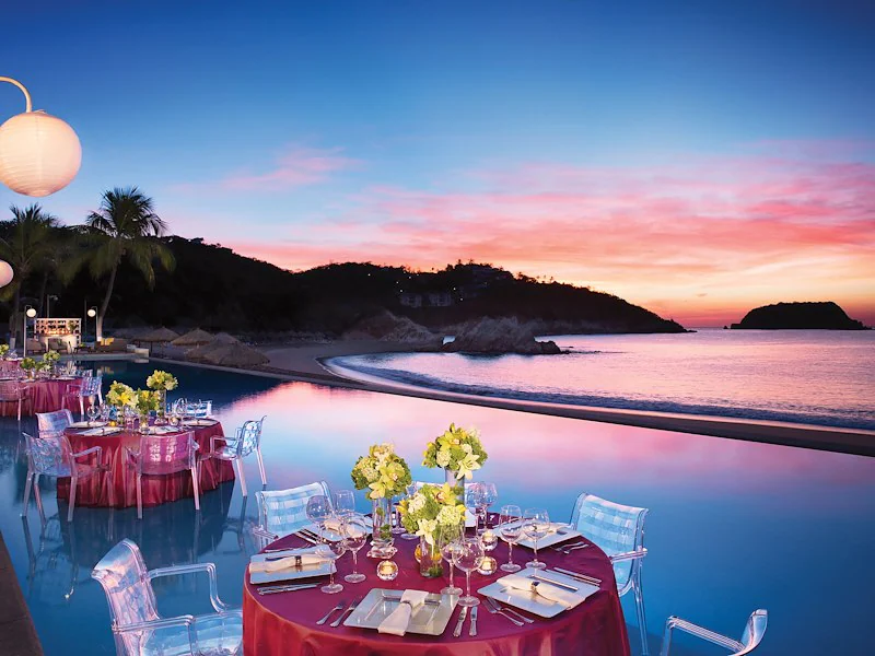 An oceanview terrace reception setup at a Mexico all-inclusive resort, lit for dinner service