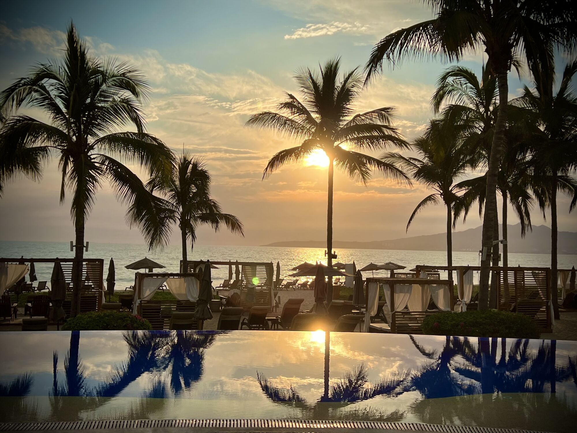 Poolside destination wedding reception at an all-inclusive resort with lit chandeliers over long banquet tables — the kind of one-property setup a resort-first approach delivers