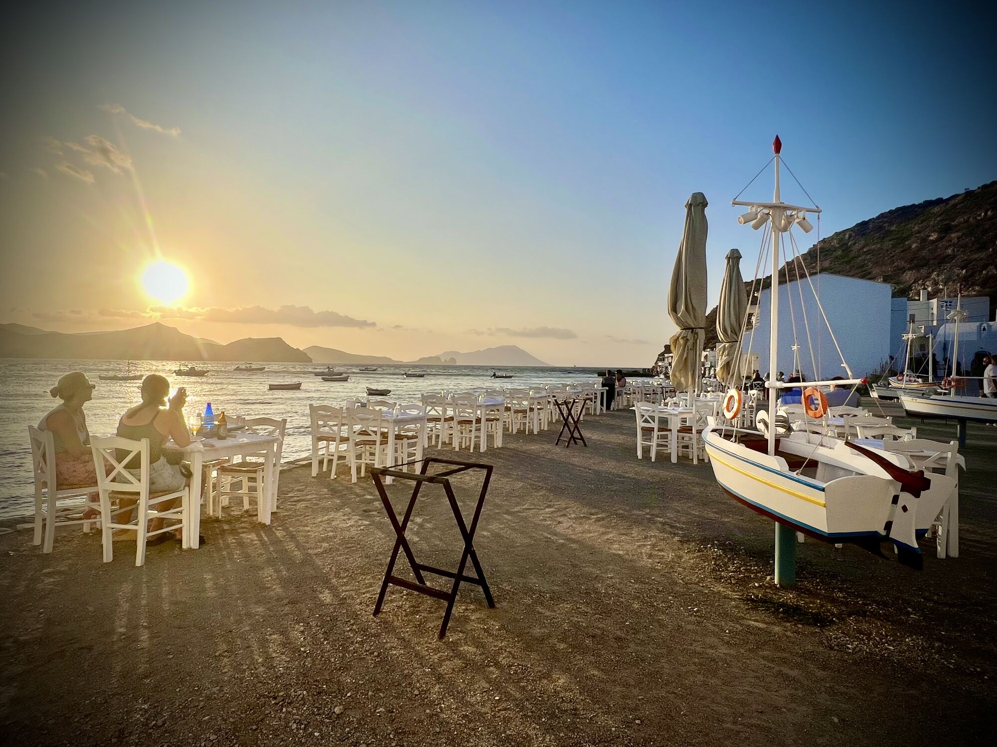 Small group of destination wedding guests gathered at a warmly-lit terrace dinner — the kind of intimate celebration a trimmed guest list makes possible