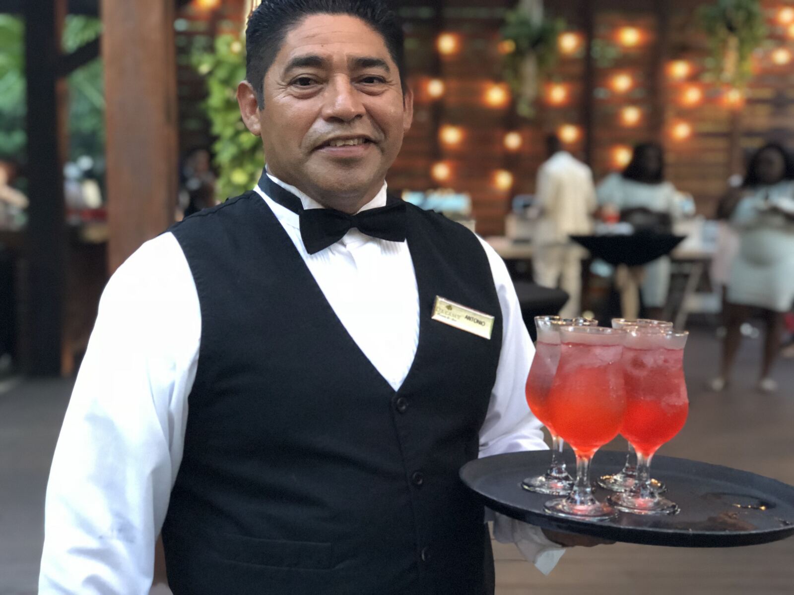 Resort server presenting a tray of hibiscus cocktails at a destination wedding reception