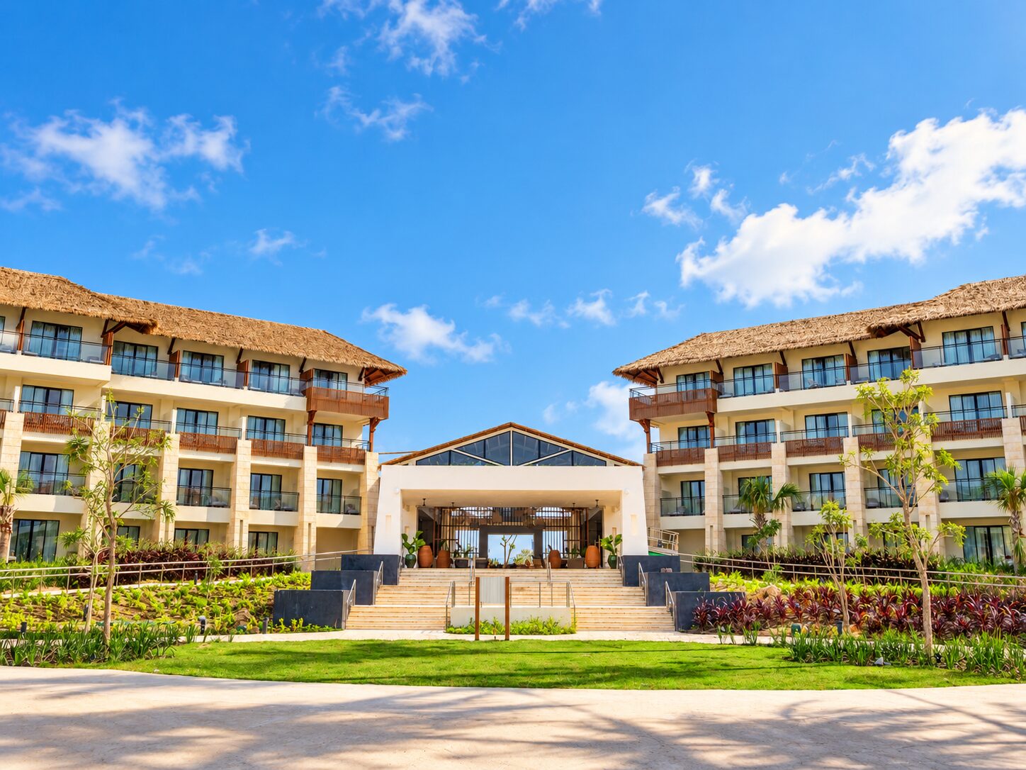 Secrets Playa Esmeralda garden lobby exterior with resort buildings, tropical landscaping, and blue sky