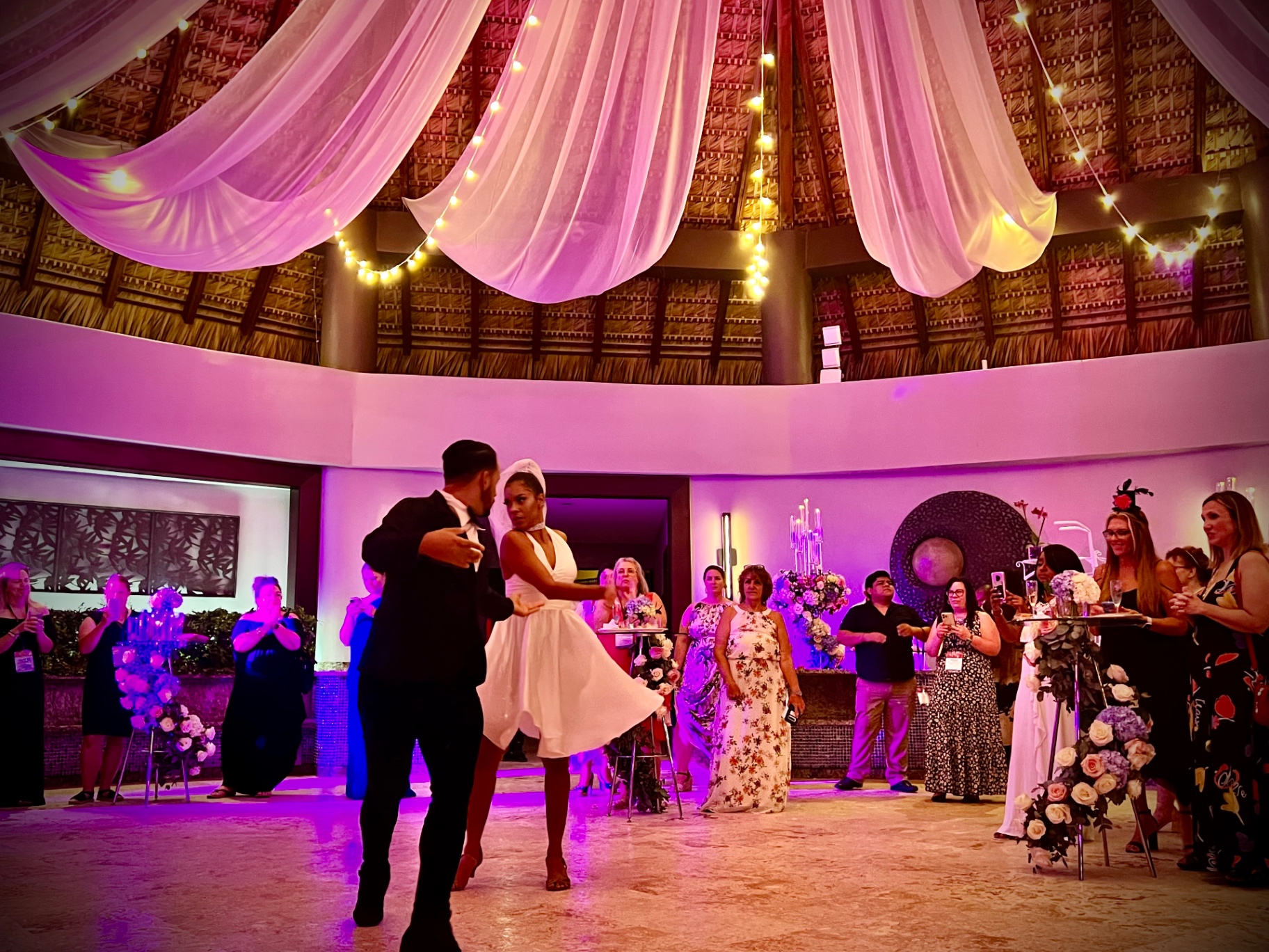 Couple dancing together at a destination wedding reception surrounded by guests