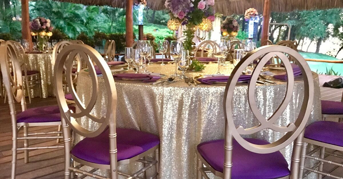 Open-air Costa Rica wedding reception with purple chairs, floral centerpieces, and tropical greenery