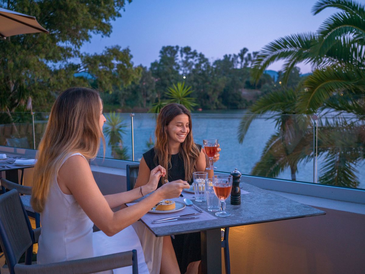 Two adult friends enjoying a relaxed dinner and toast at a destination resort, no children present
