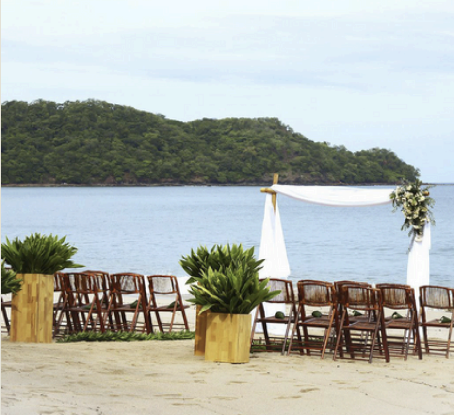 Wedding ceremony chairs and floral arch on the beach at W Costa Rica Reserva Conchal with ocean and headland view