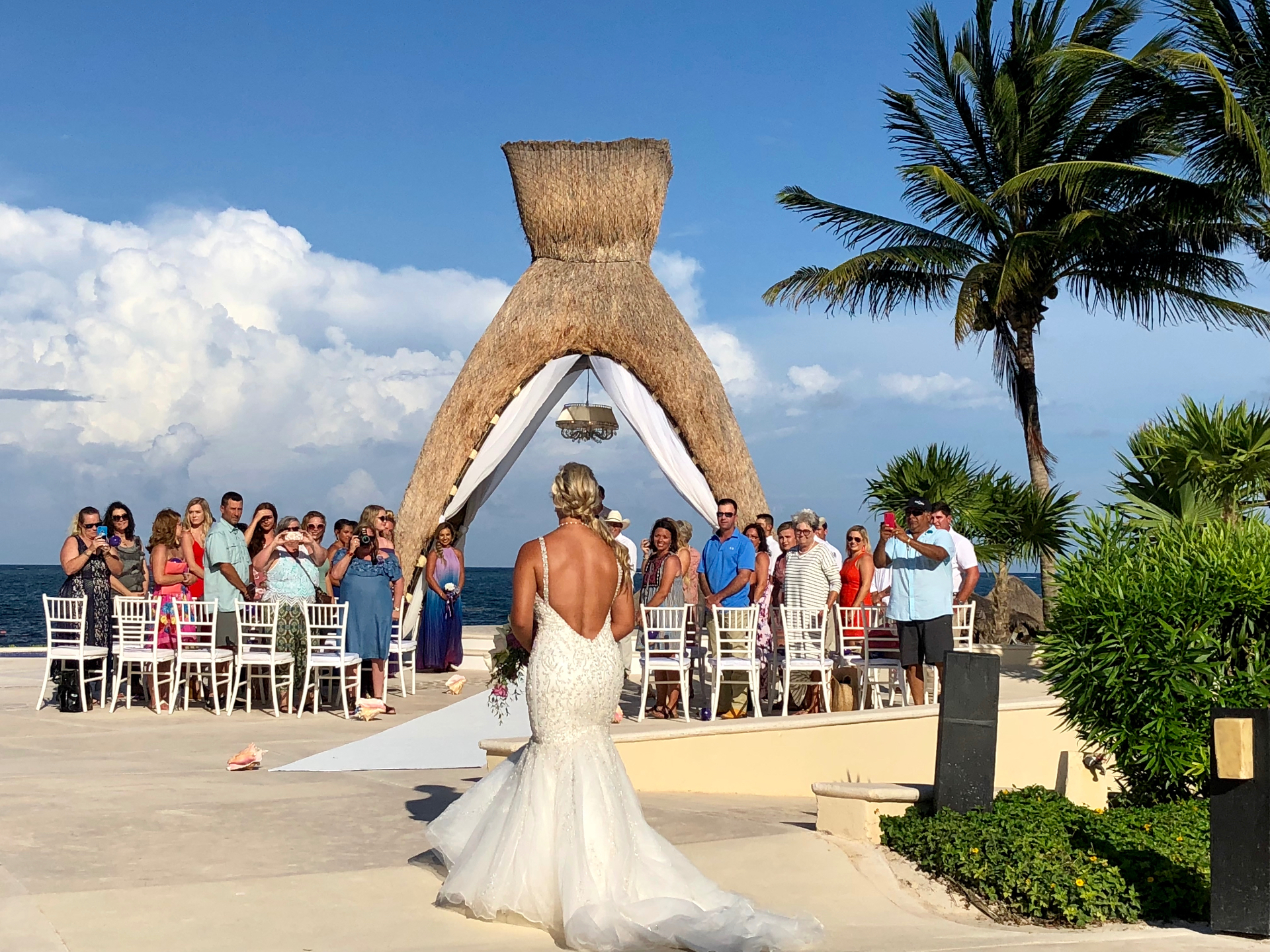 Bride and groom facing an officiant during a barefoot oceanfront ceremony — the classic aisle-reveal moment couples preserve when they skip a first look