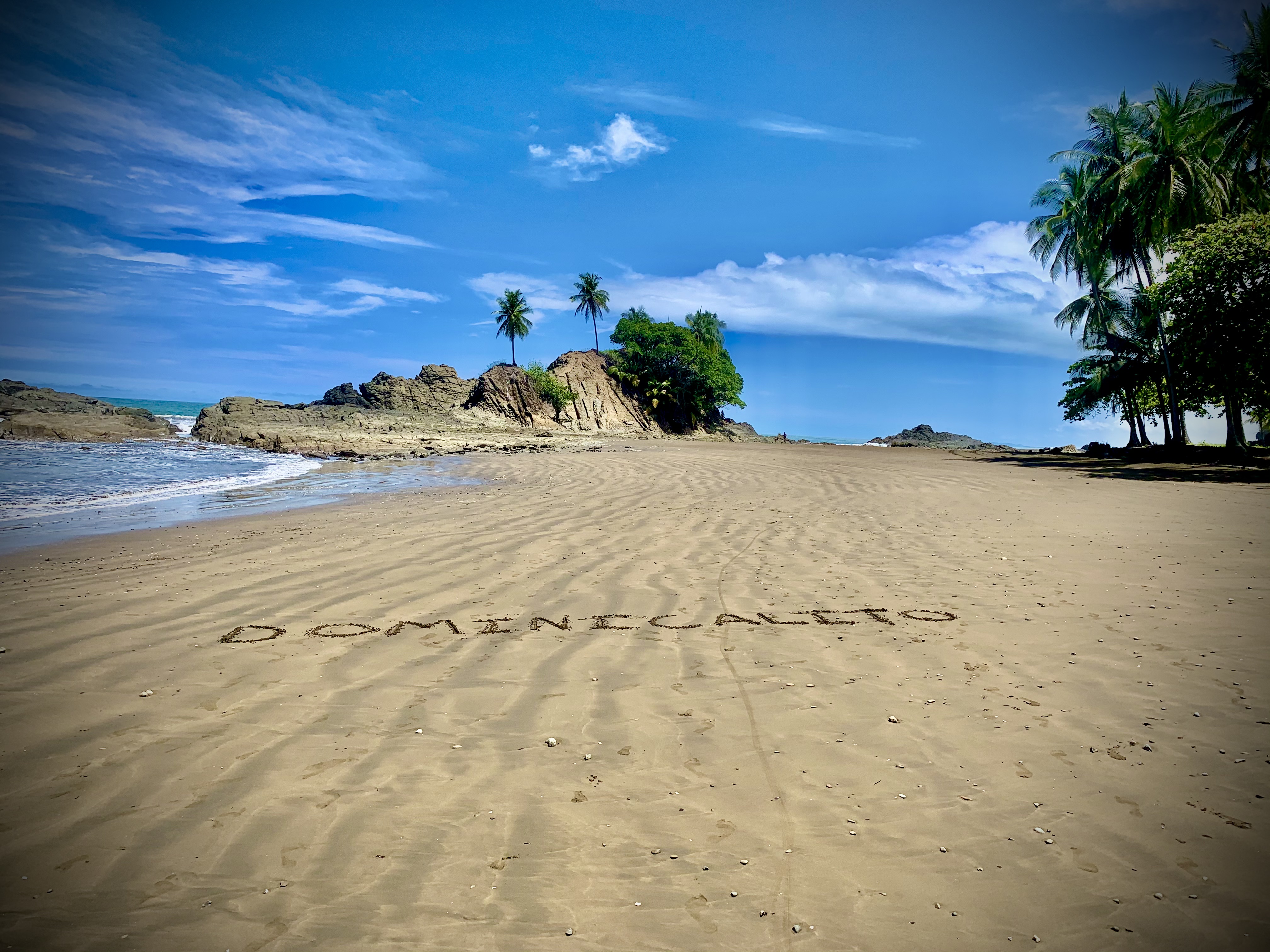 Dominicalito Beach in Costa Rica with palm trees, rocky shoreline, and ocean views
