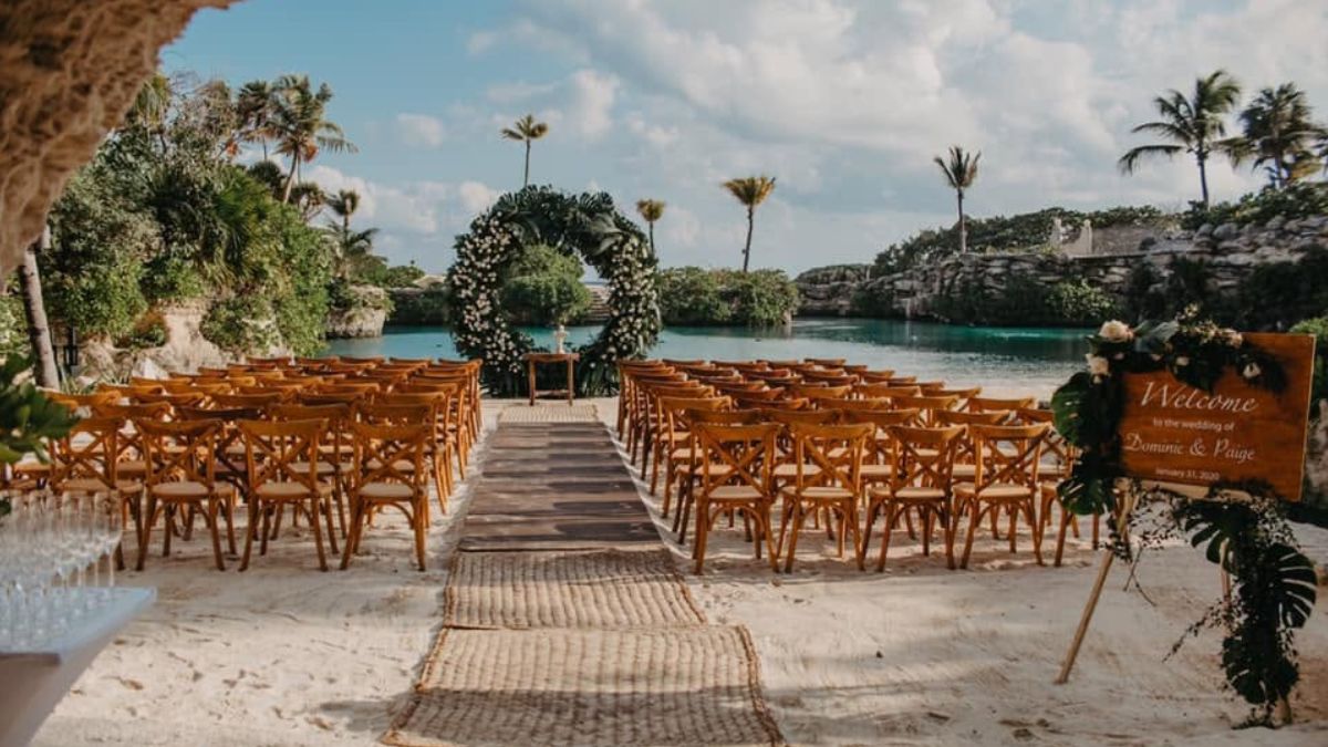 Outdoor wedding ceremony aisle setup with a floral arch overlooking a lagoon at Hotel Xcaret, Mexico