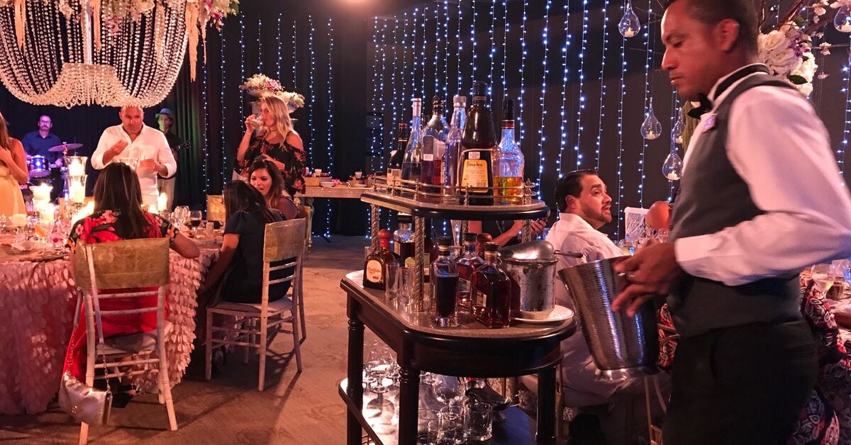 Costa Rica wedding reception with a bar cart, floral chandelier, candlelit tables, and twinkle lights