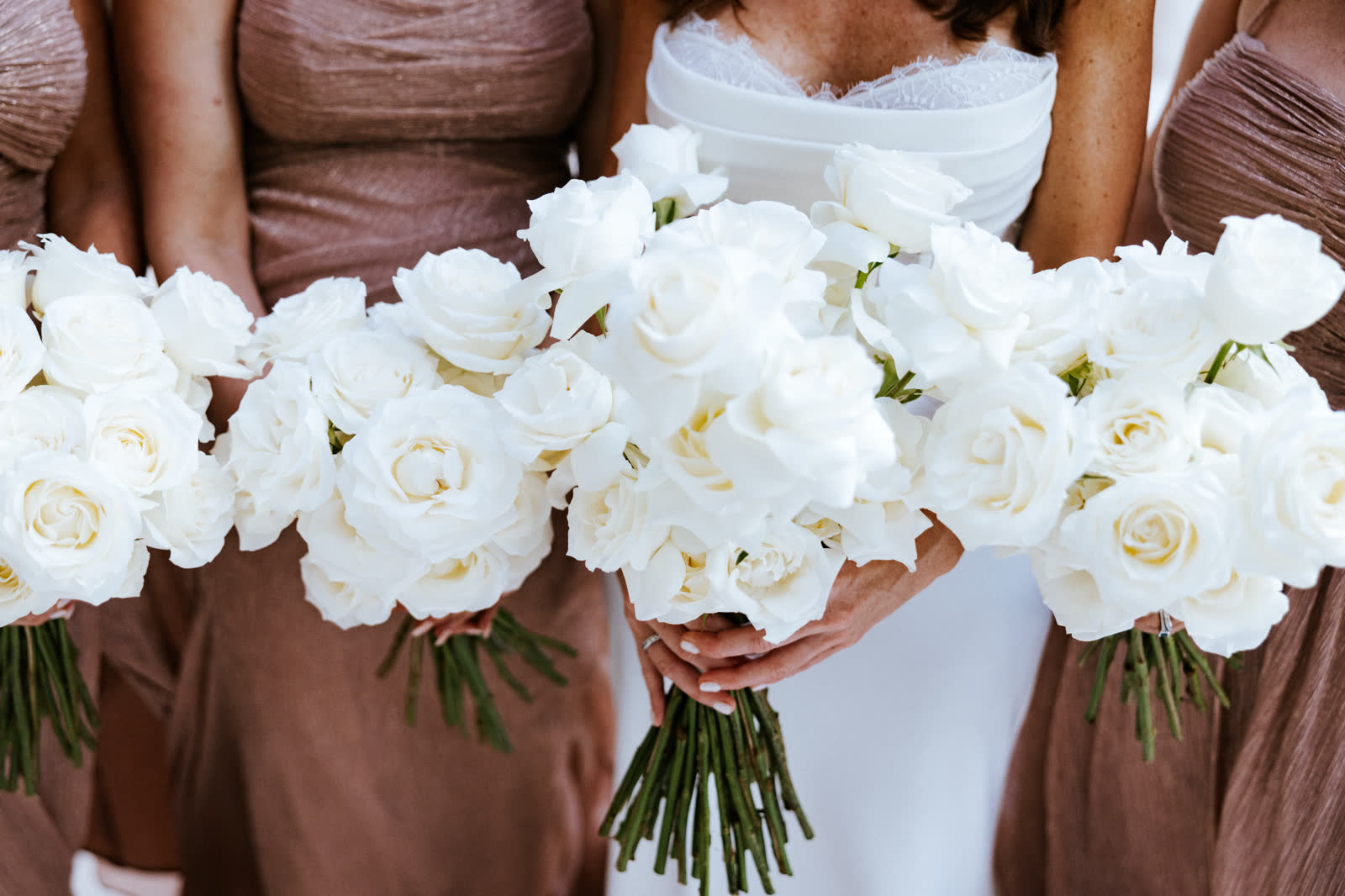 Bride and bridesmaids holding white rose bouquets