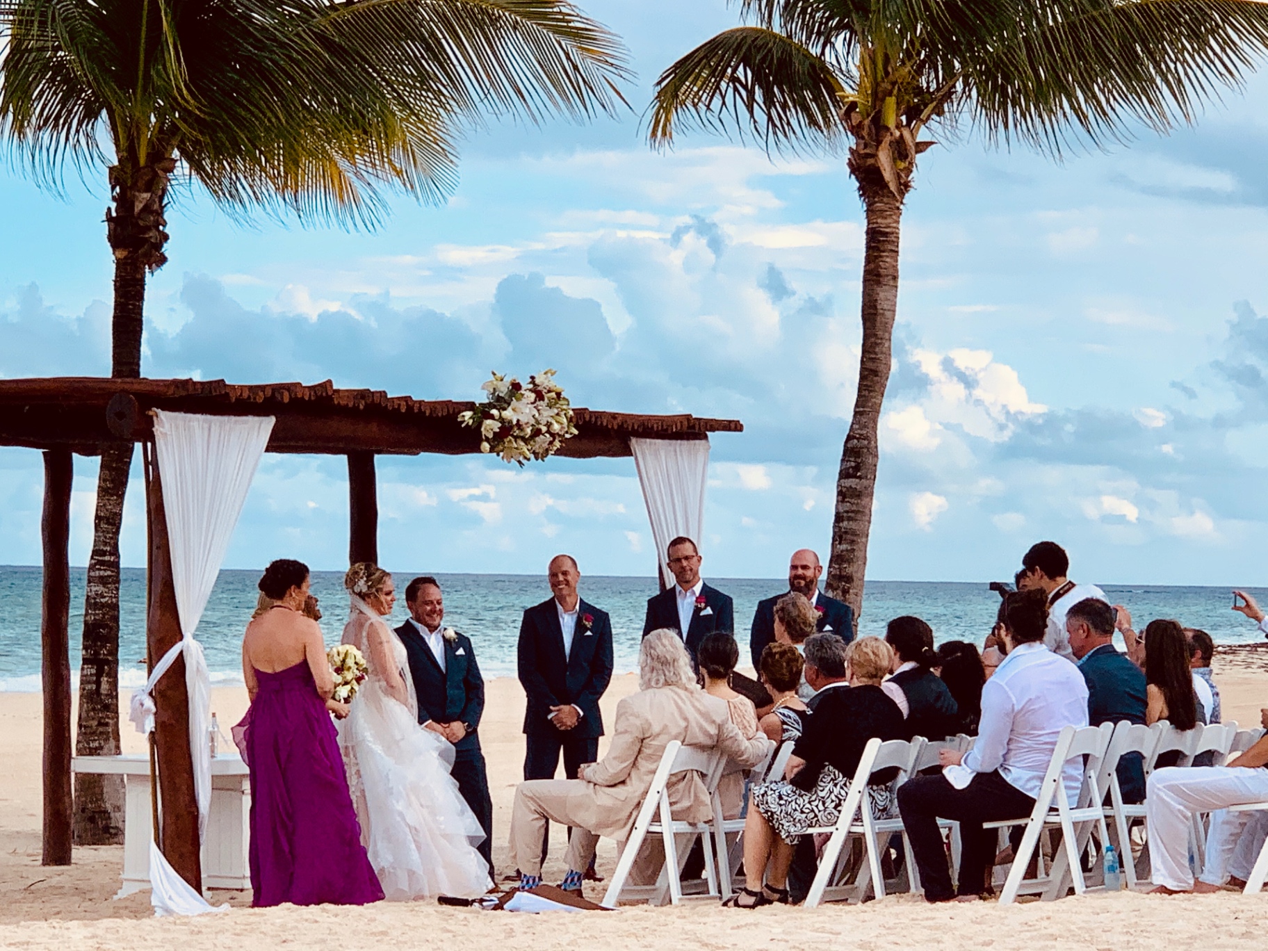 Wedding guests cheering on the beach after the ceremony