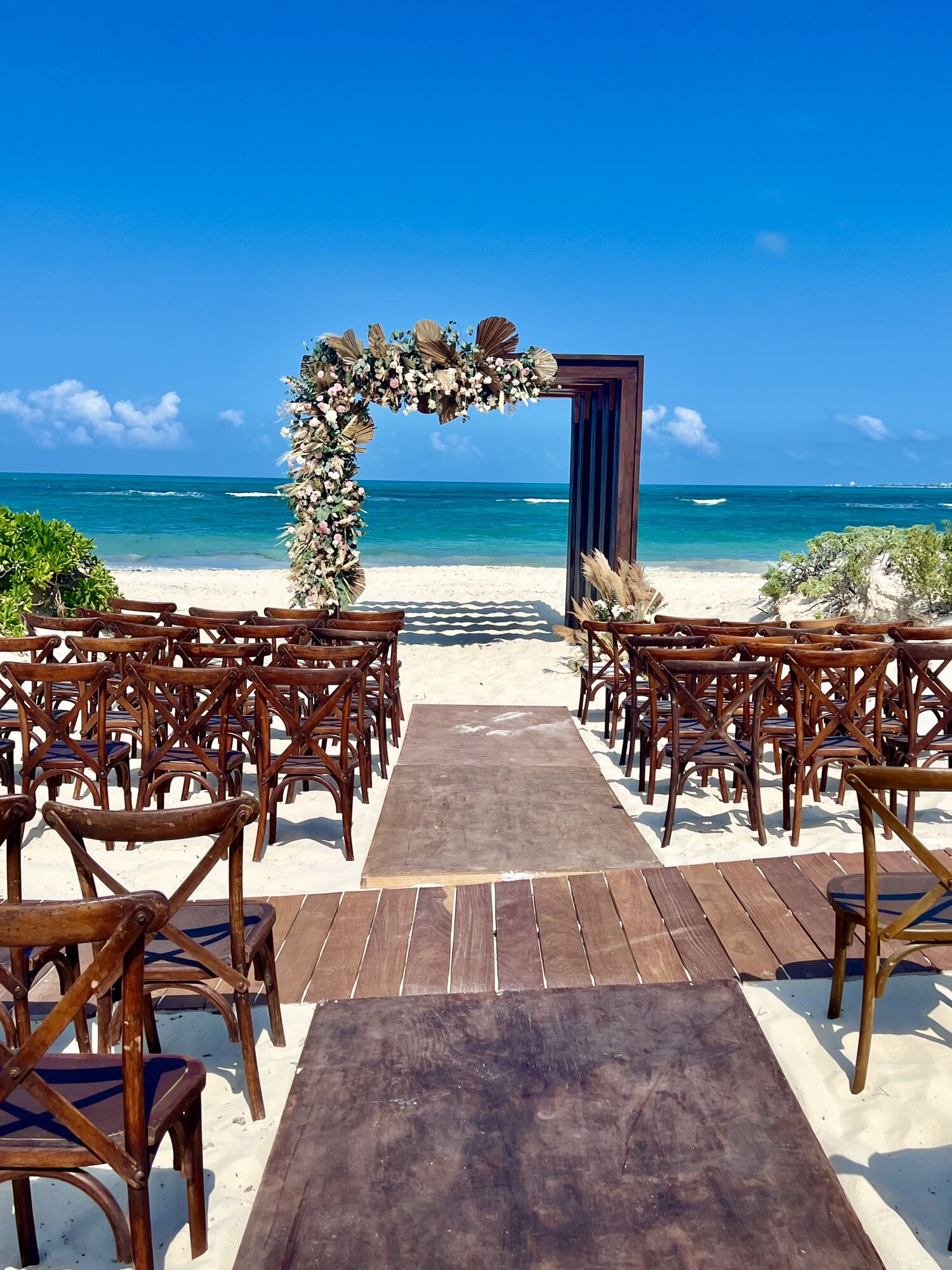 Floral ceremony arch mid-setup at a destination wedding venue — the kind of scene where an outside florist, an indoor backup space, and a clear weather call-to-move all have to be spelled out in the venue contract before the crew arrives
