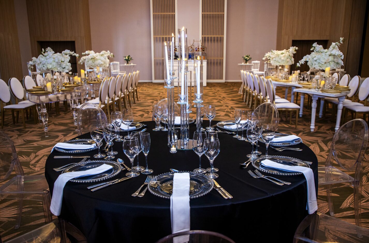 Indoor ballroom reception at Secrets & Dreams Playa Esmeralda with black table linens, white floral centerpieces, and candlelit place settings