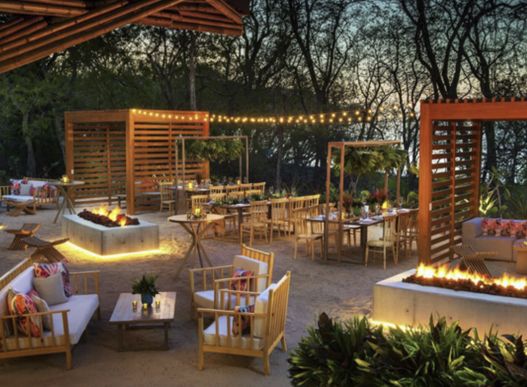 Zona Azul Beach Club lounge area with fire pits and wood slat screens at W Costa Rica Reserva Conchal at dusk