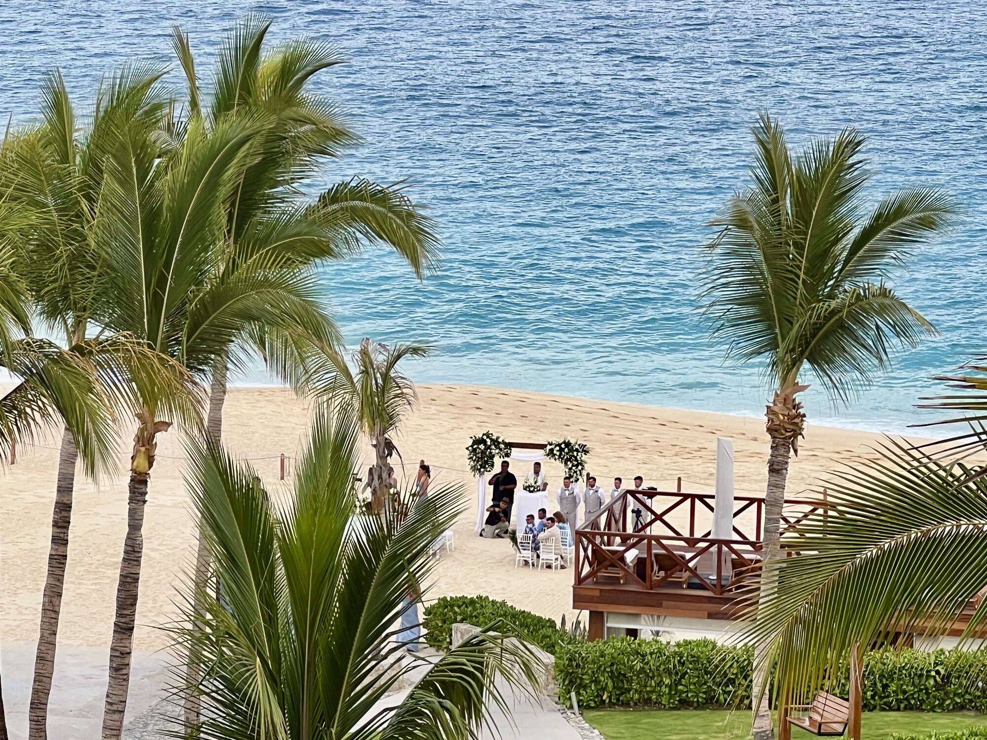 Cliffside sunset ceremony under stone columns at a destination wedding — the kind of vision couples fall in love with, and the exact kind of choice that most often triggers a wave of guest pushback in the weeks after the save-the-date goes out