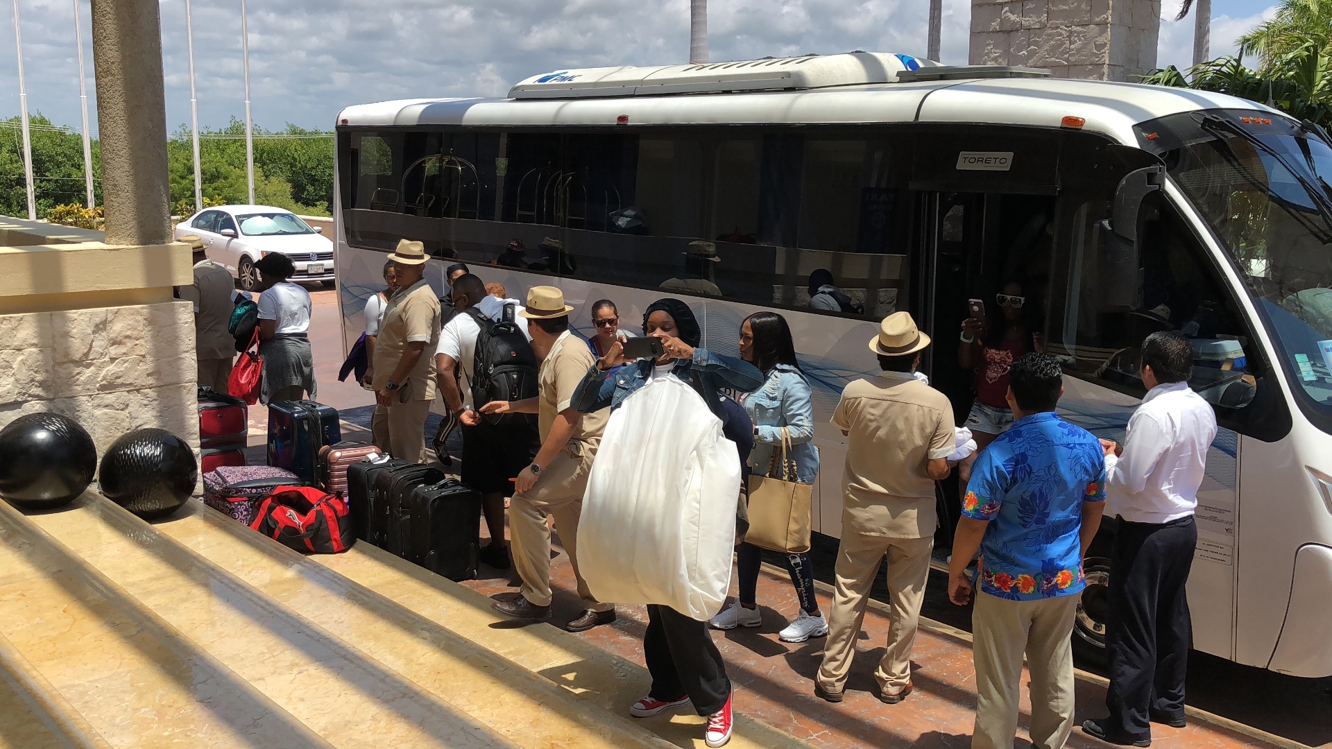 Wedding guests arriving at a resort with luggage after a group shuttle transfer.