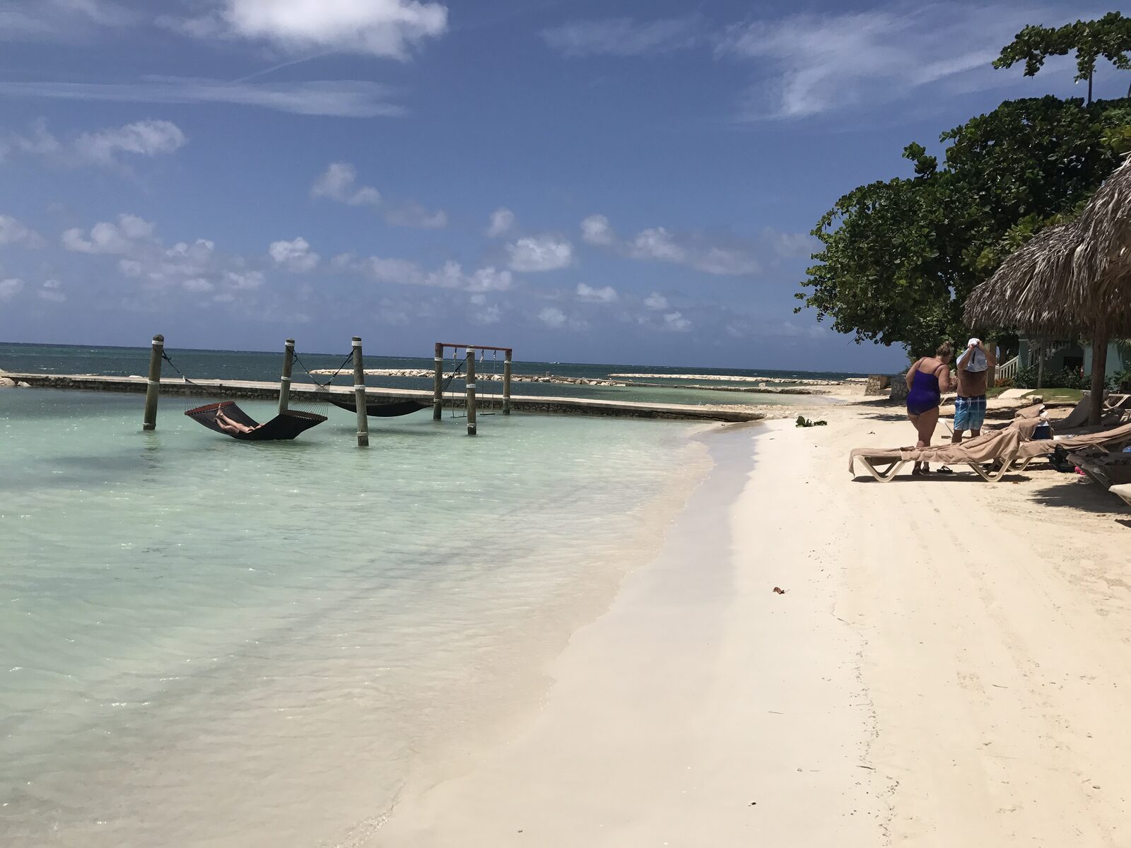 Beach hammocks strung between palms over a wooden dock, the kind of quiet spot to escape to before the ceremony