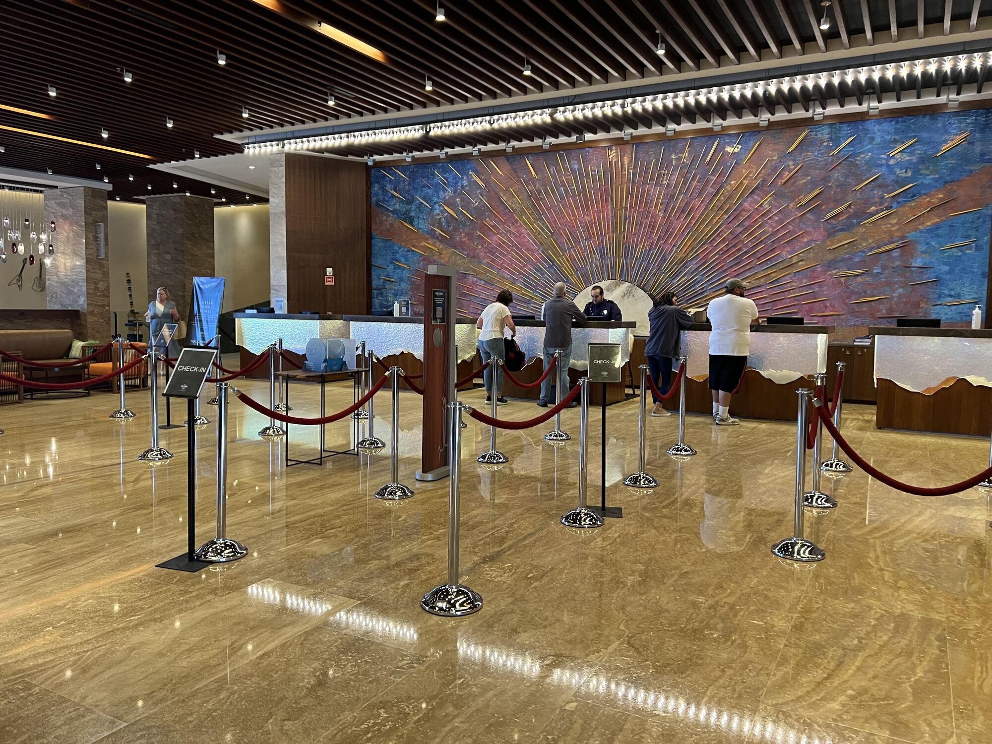Destination wedding guests checking in together at a resort welcome desk with complimentary wine — group perks routed back to guests as a welcome moment