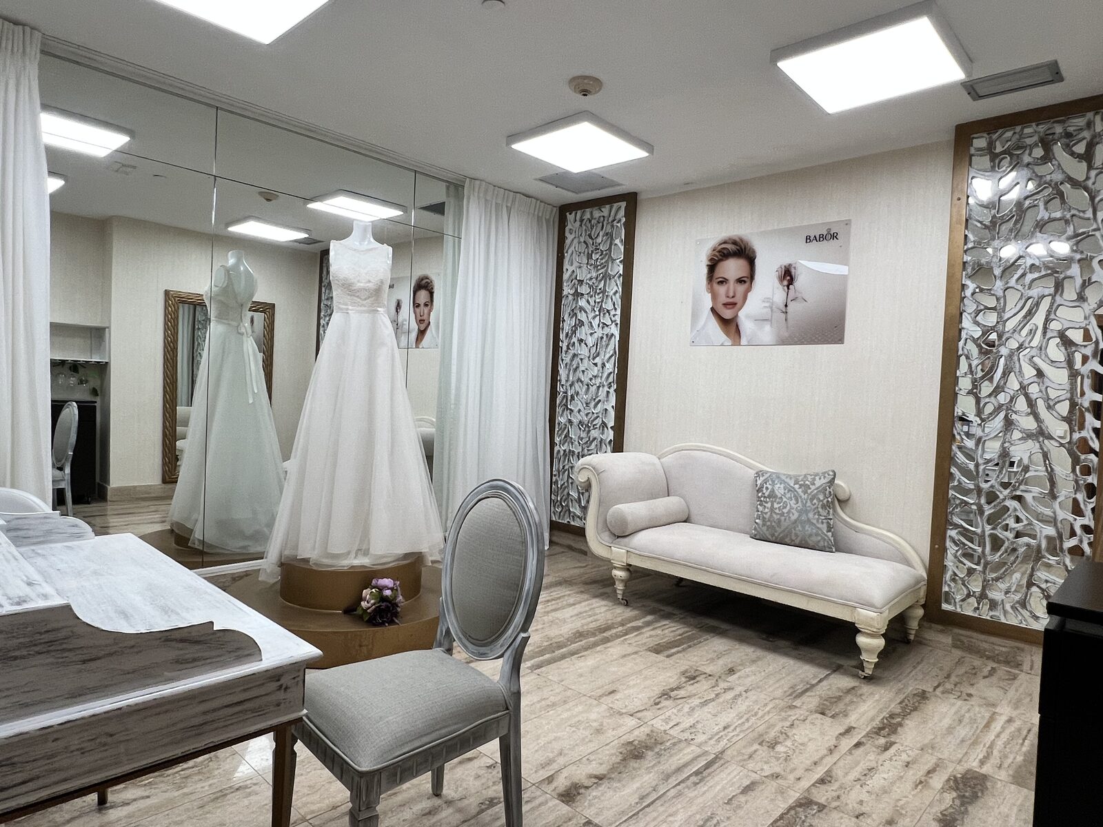 A bride in a bridal boutique fitting room preparing her gown, the moment where the packing conversation should start with the salon before the trip